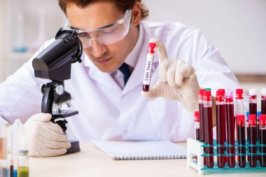 Genç yakışıklı laboratuvar asistanı hastanede kan örnekleri test ediyor. 