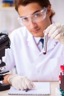 Genç yakışıklı laboratuvar asistanı hastanede kan örnekleri test ediyor. 