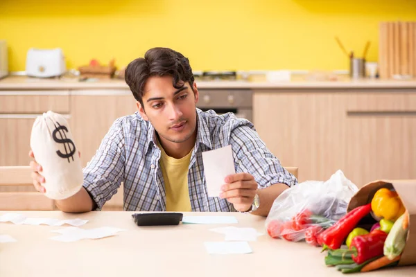 Mladý muž počítá výdaje na zeleninu v kuchyni — Stock fotografie