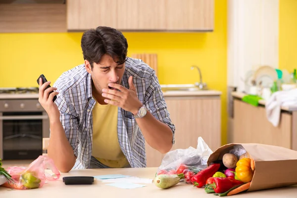 Junger Mann berechnet Ausgaben für Gemüse in der Küche — Stockfoto