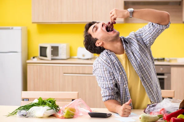 Junger Mann berechnet Ausgaben für Gemüse in der Küche — Stockfoto