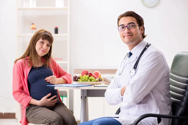 Mujer embarazada visitando al médico discutiendo dieta saludable —  Fotos de Stock