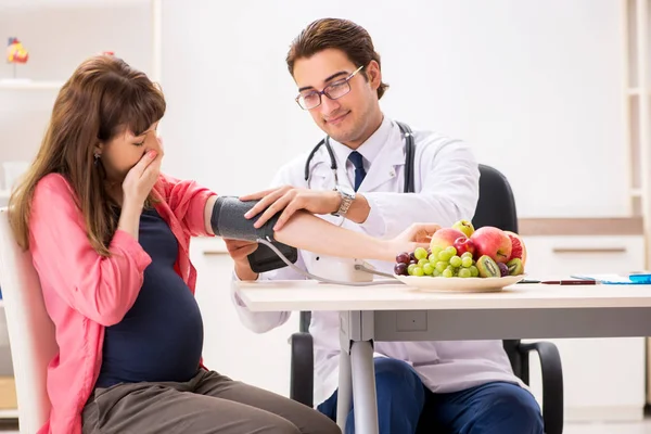 Pregnant woman visiting doctor discussing healthy diet — Stock Photo, Image