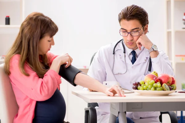 Mujer embarazada visitando al médico discutiendo dieta saludable — Foto de Stock