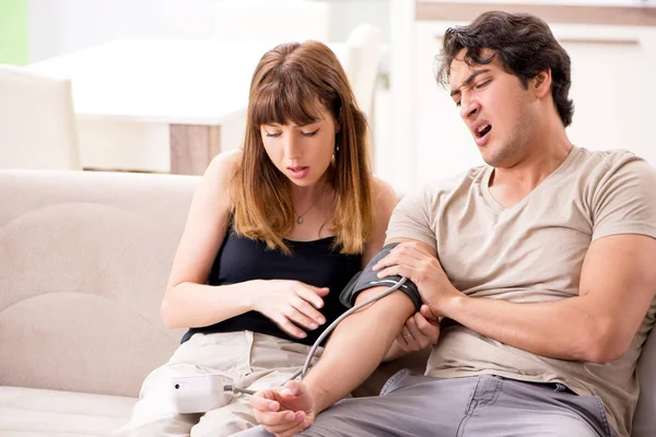 Esposa chequeando maridos presión arterial — Foto de Stock
