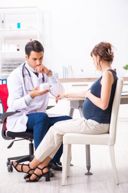 Genç doktor hamile kadınların kan basıncını ölçüyor.