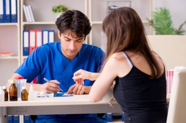 Kolu bandajlı genç kadın erkek doktor traumotologis 'i ziyaret ediyor.