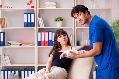 Kolu bandajlı genç kadın erkek doktor traumotologis 'i ziyaret ediyor.