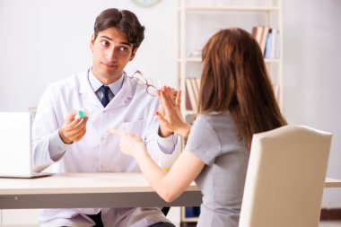 Genç bir kadın, erkek doktor göz doktorunu hastanede ziyaret ediyor.
