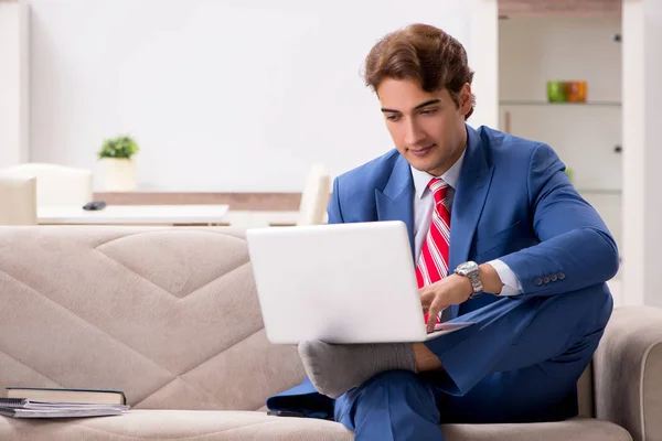 Молодий бізнесмен працює вдома, сидячи на дивані — стокове фото
