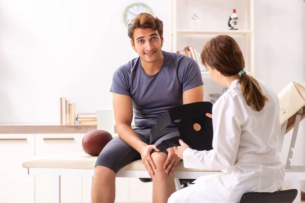 Guapo americano futbolista visitando mujer médico traumato — Foto de Stock