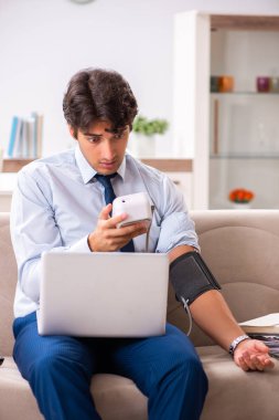 Stres altındaki adam kan basıncını ölçüyor.