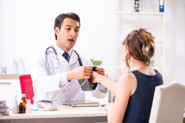 Genç doktor, kadınların tansiyonunu ölçüyor.