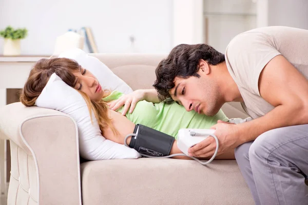 Mąż sprawdza ciężarne żony ciśnienie krwi — Zdjęcie stockowe
