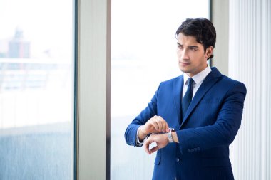 Genç yakışıklı işadamı pencerede duruyor. 