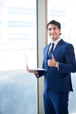 Genç yakışıklı işadamı pencerede duruyor. 