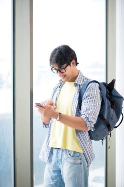 Genç yakışıklı öğrenci pencerede duruyor. 