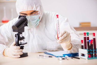 Genç yakışıklı laboratuvar asistanı hastanede kan örnekleri test ediyor. 