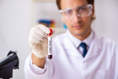 Genç yakışıklı laboratuvar asistanı hastanede kan örnekleri test ediyor. 