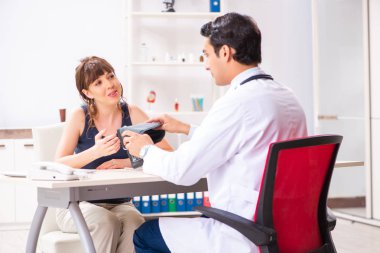 Genç doktor, kadınların tansiyonunu ölçüyor.