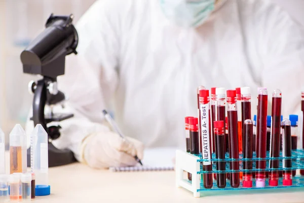 Asistente de laboratorio joven guapo analizando muestras de sangre en el hospital — Foto de Stock