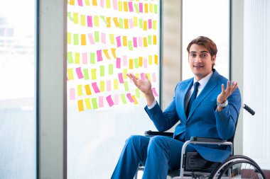 Birçok çelişkili önceliği olan tekerlekli sandalyedeki genç yakışıklı adam.