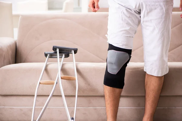 Joven con la rodilla lesionada recuperándose en casa — Foto de Stock
