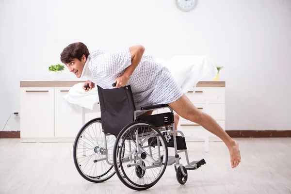 Junger schöner Mann im Rollstuhl im Krankenhaus — Stockfoto