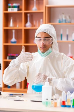 Laboratuvarda çalışan koruyucu elbise giyen genç bir biyokimyacı.