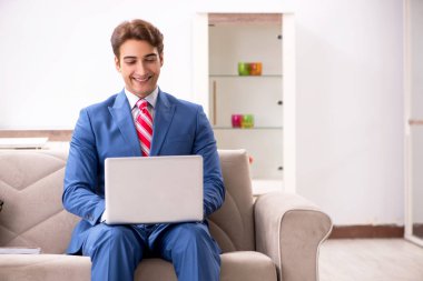 Genç işadamı evde çalışıyor, kanepede oturuyor. 
