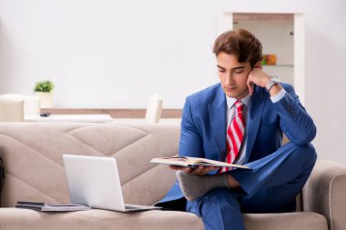 Genç işadamı evde çalışıyor, kanepede oturuyor. 