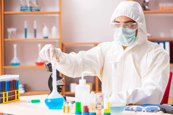 Молодий біохімік в захисному костюмі працює в лабораторії — стокове фото