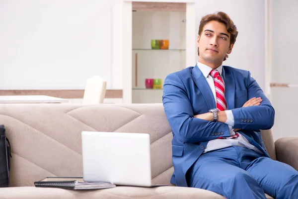 若いビジネスマンはソファに座って家で働いている — ストック写真
