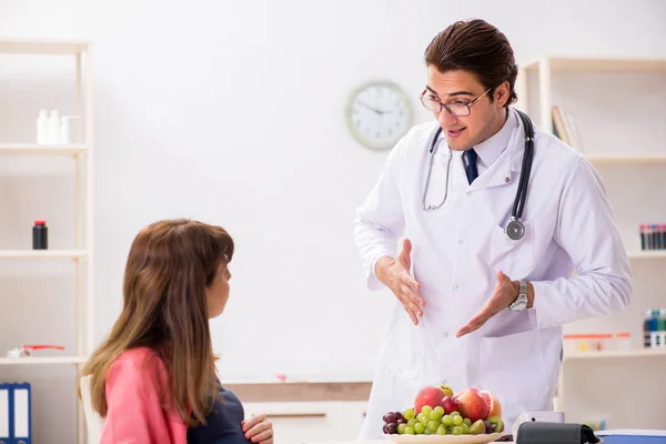 Беременная женщина посещает врача, обсуждая здоровую диету — стоковое фото