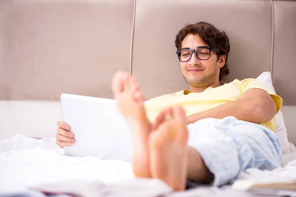 Estudante com laptop deitado na cama — Fotografia de Stock