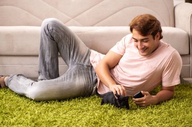 Genç adam evde kedi yavrusuyla oynuyor.