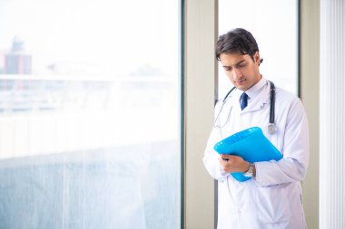 Genç yakışıklı doktor pencerede duruyor. 
