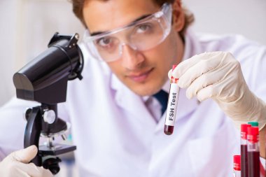 Genç yakışıklı laboratuvar asistanı hastanede kan örnekleri test ediyor. 