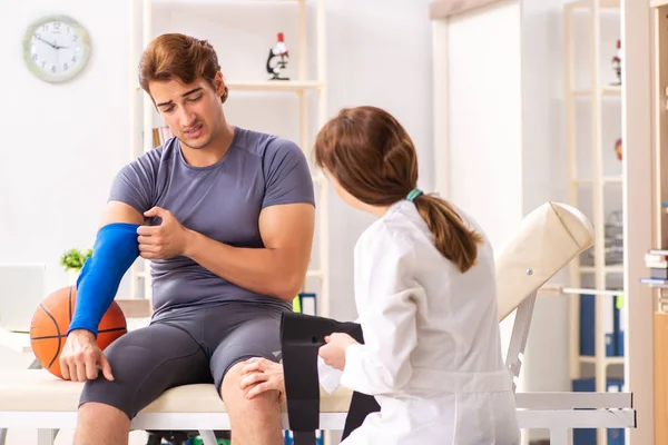 Guapo jugador de baloncesto visitando médico traumatólogo femenino — Foto de Stock