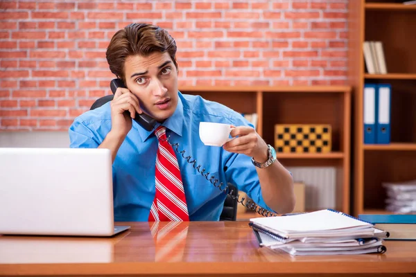 Young employee with excessive work sitting at the office