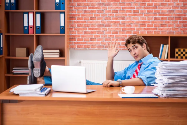 Ung anställd med överdrivet arbete sittande på kontoret — Stockfoto