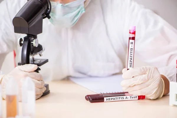 Asistente de laboratorio joven guapo analizando muestras de sangre en el hospital — Foto de Stock