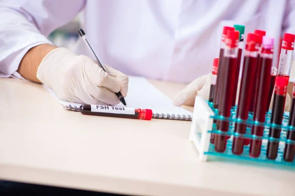 Asistente de laboratorio joven guapo analizando muestras de sangre en el hospital — Foto de Stock