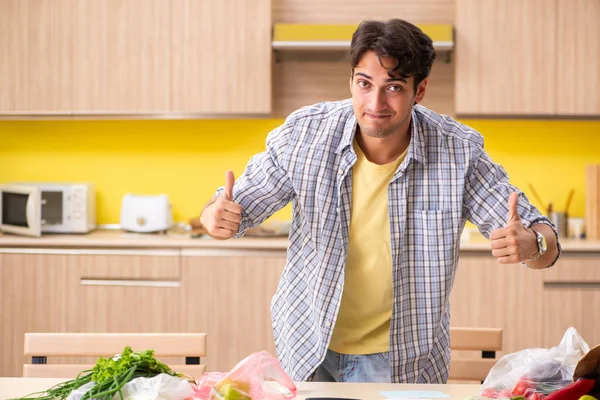 Fiatalember kiszámítja a zöldségkiadásokat a konyhában — Stock Fotó