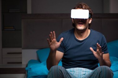 Genç adam, gece yatakta ile bilgisayar oyunu oynamak