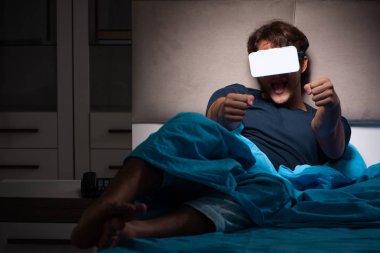 Genç adam, gece yatakta ile bilgisayar oyunu oynamak