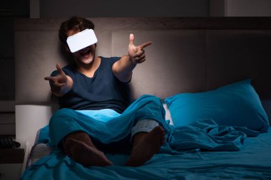 Genç adam, gece yatakta ile bilgisayar oyunu oynamak