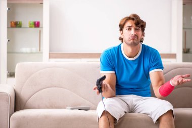 Yaralı kollu kanepede oturan genç adam 