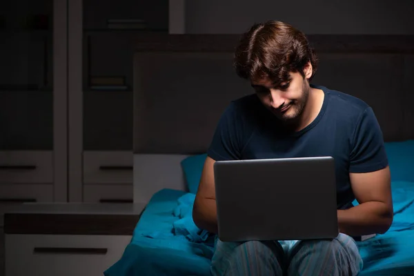 Uomo che lavora sul computer portatile di notte a letto — Foto Stock