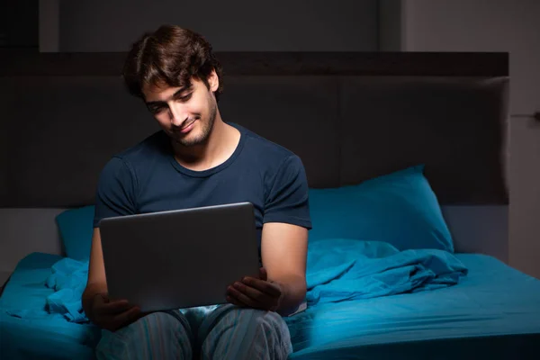 Man som arbetar på bärbara dator på natten i sängen — Stockfoto